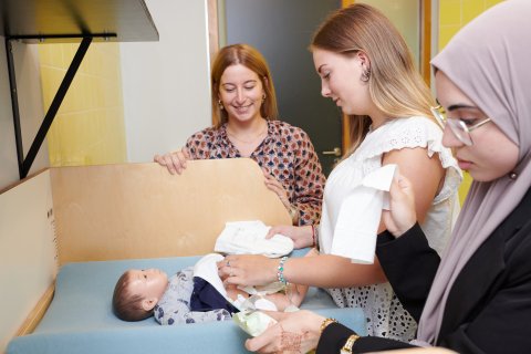 Twee studenten krijgen uitleg over het verzorgen van een baby.