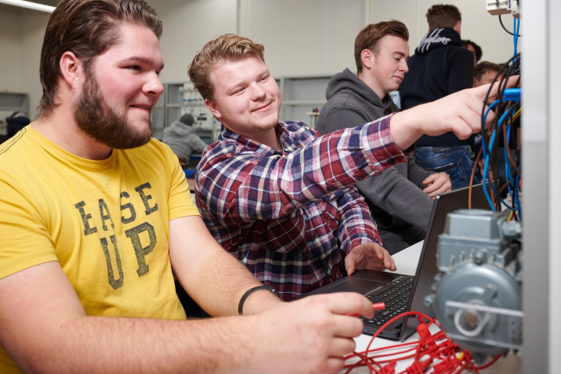 Student wijst naar een technische installatie om iets aan een andere student te laten zien