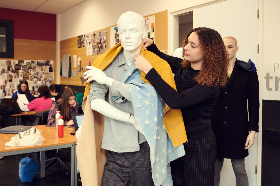 Student fashion designer probeert een ontwerp op de paspop