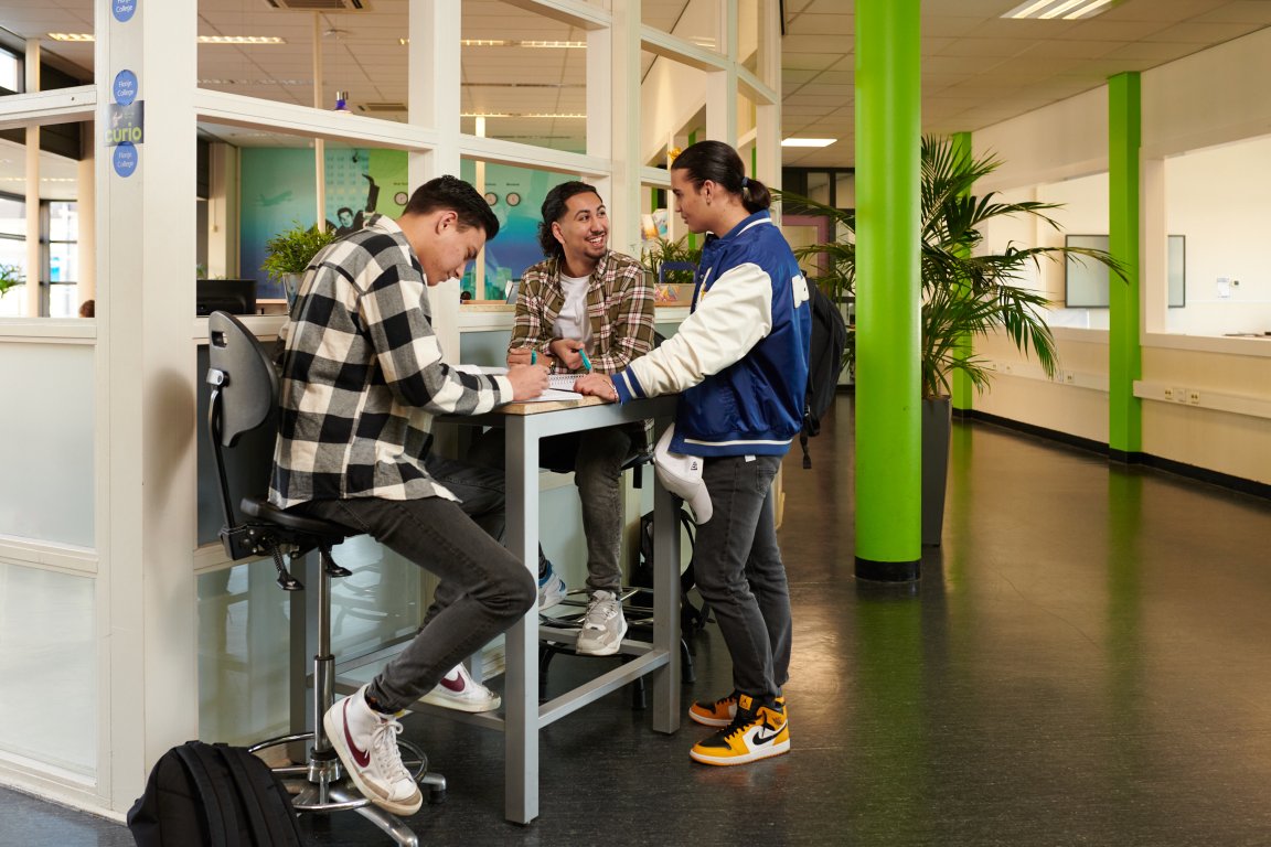 Drie studenten aan hoge tafel in gesprek