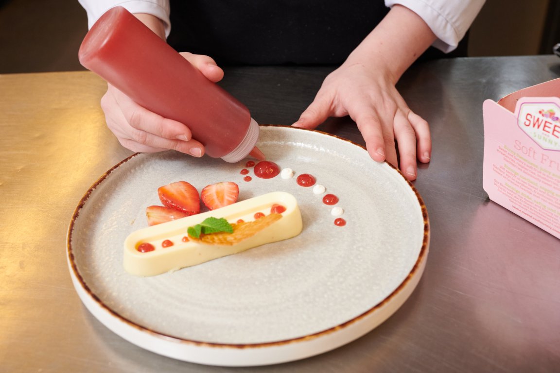 Chique dessert waar met een fles aardbeiensaus nog de finishing touch aan wordt gegeven