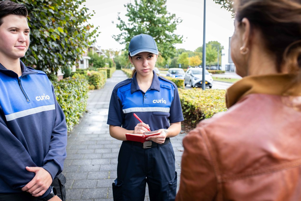 Twee studenten handhaving houden een vrouw staande en een van de studenten schrijft notities op in een klein boekje