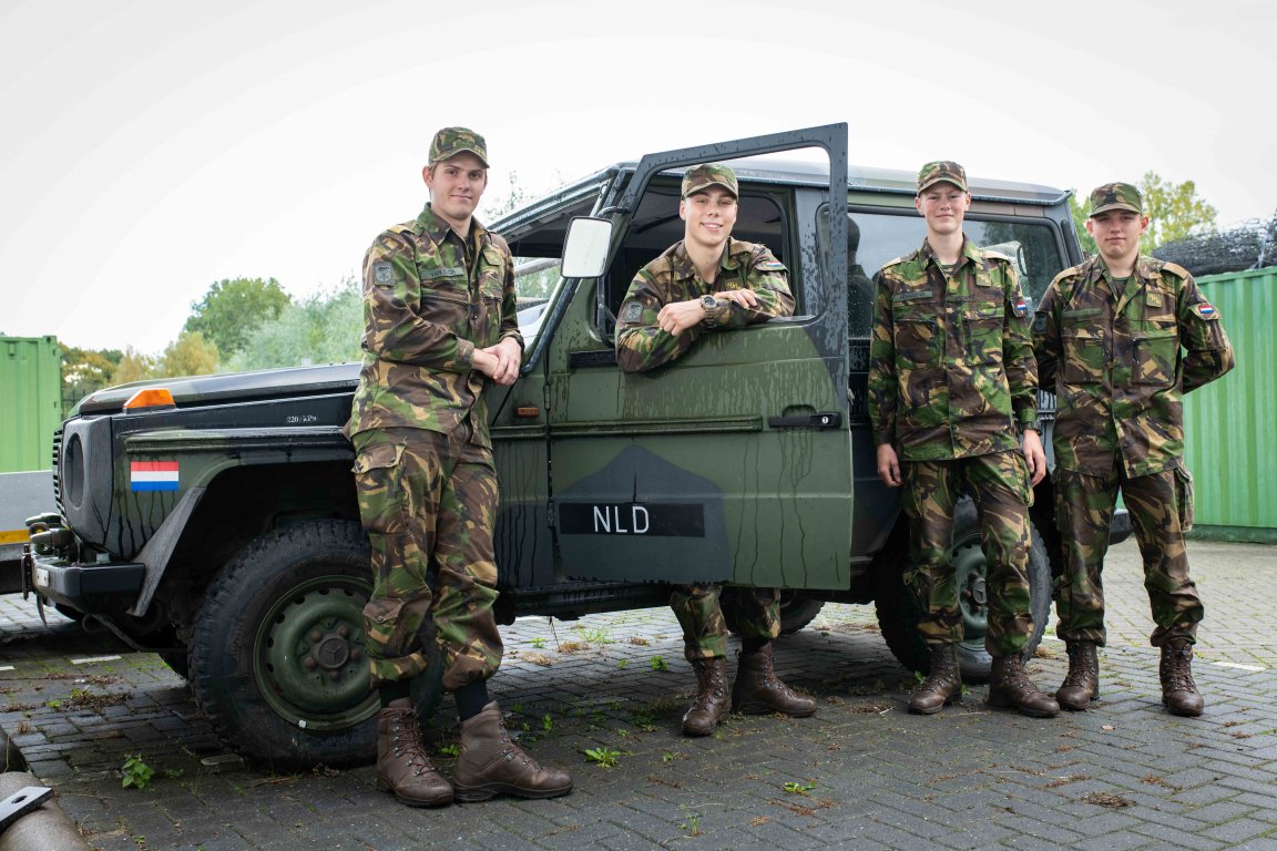 Vier studenten in uniform bij de bedrijfsauto 